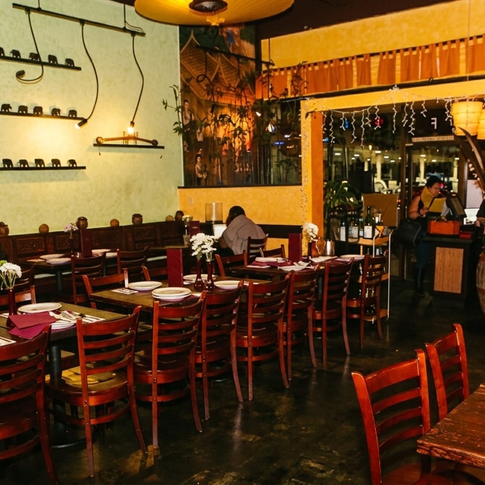 Cozy restaurant interior with bamboo decor, elephant figurines, and diners at tables.