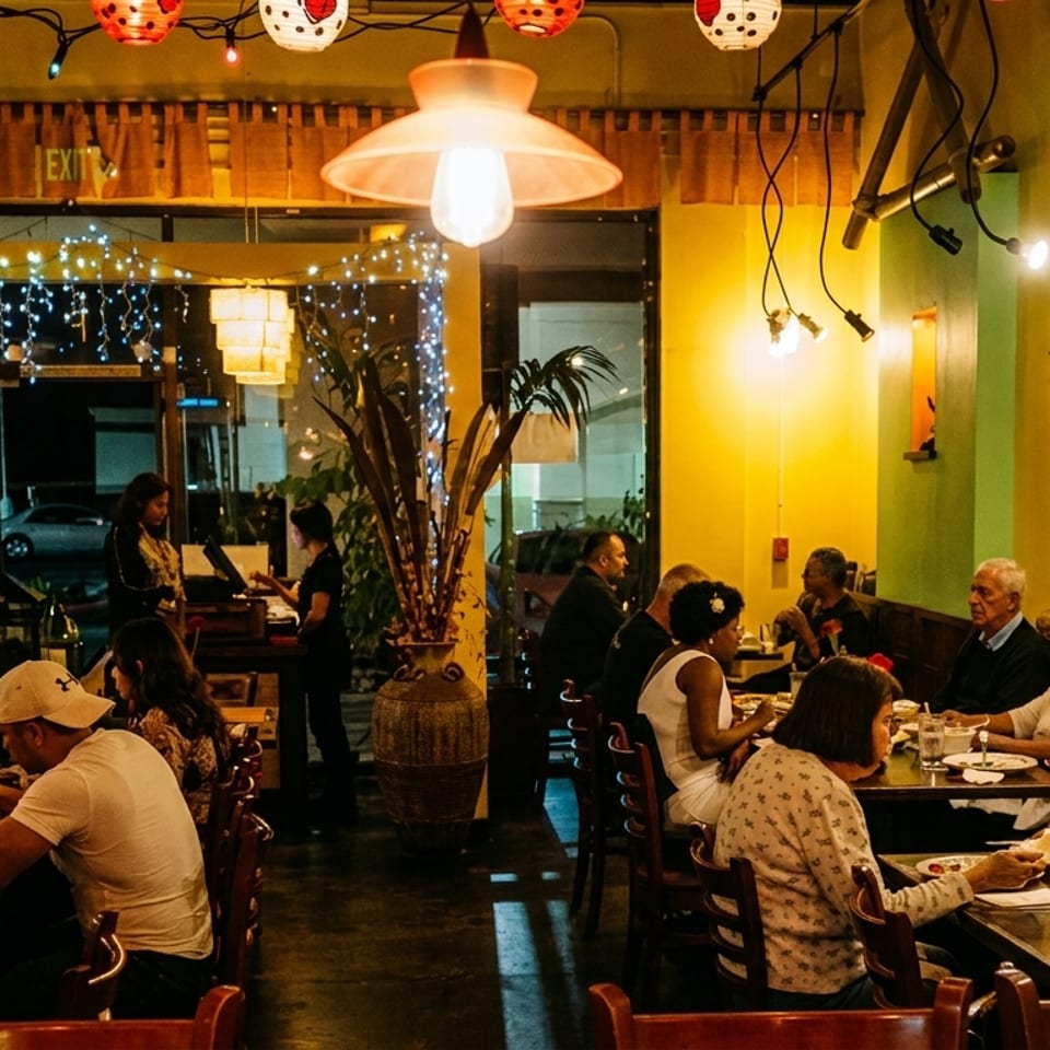Diners enjoying meals in a vibrant restaurant with warm lighting and festive decorations.